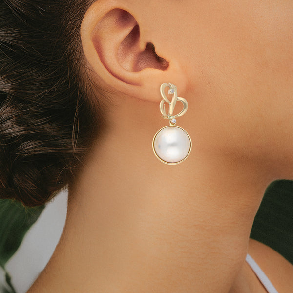 Aretes calados con colgantes, medias perlas y circonias en oro amarillo 14 kilates.