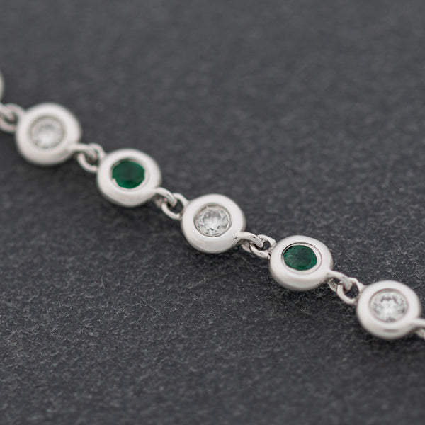 Pulsera eslabón combinado con aplicaciones de diamantes y esmeraldas en oro blanco 14 kilates.