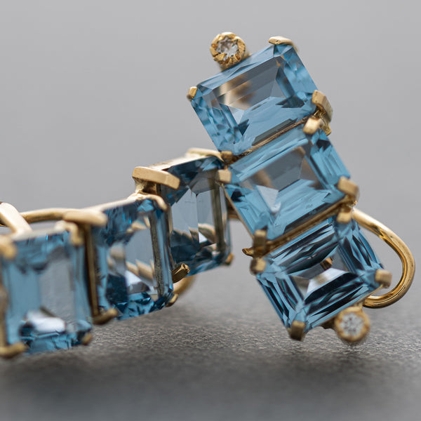 Juego de anillo y aretes estilizados con diamantes y topacios azules en oro amarillo 14 kilates.