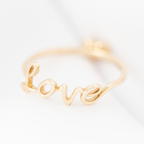 Anillo diseño especial motivo letras y corazón con circonias en oro amarillo 14 kilates.