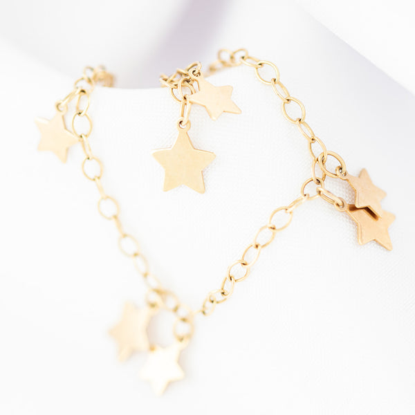 Pulsera eslabón cruzado con colgantes motivo estrellas en oro amarillo 14 kilates.