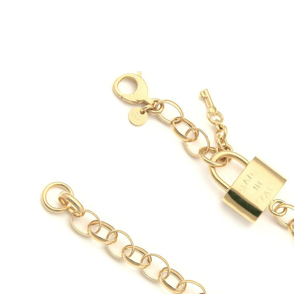 Pulsera eslabón cruzado con aplicación y colgante motivo candado y llave en oro amarillo 14 kilates.