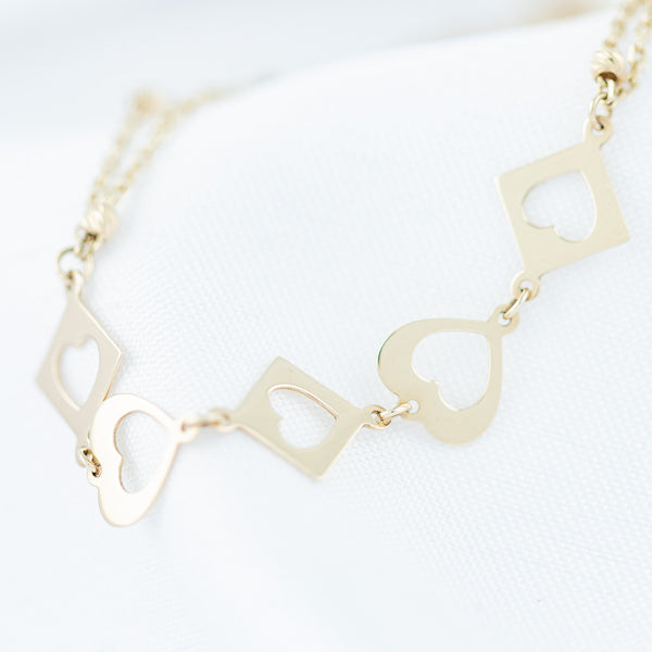 Pulsera dos hilos eslabón cruzado con aplicaciones motivo rombo y corazón en oro amarillo 14 kilates.