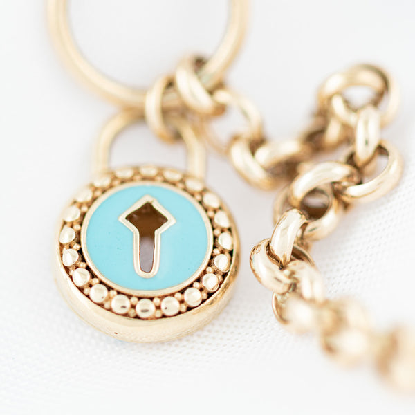 Pulsera eslabón cruzado con colgante motivo candado y esmalte en oro amarillo 14 kilates.