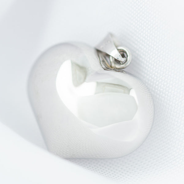 Dije hueco motivo corazón en oro blanco 14 kilates.