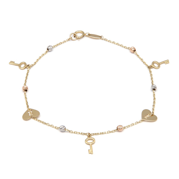 Pulsera eslabón cruzado con aplicaciones y colgantes motivo llaves y corazón en oro tres tonos 14 kilates.