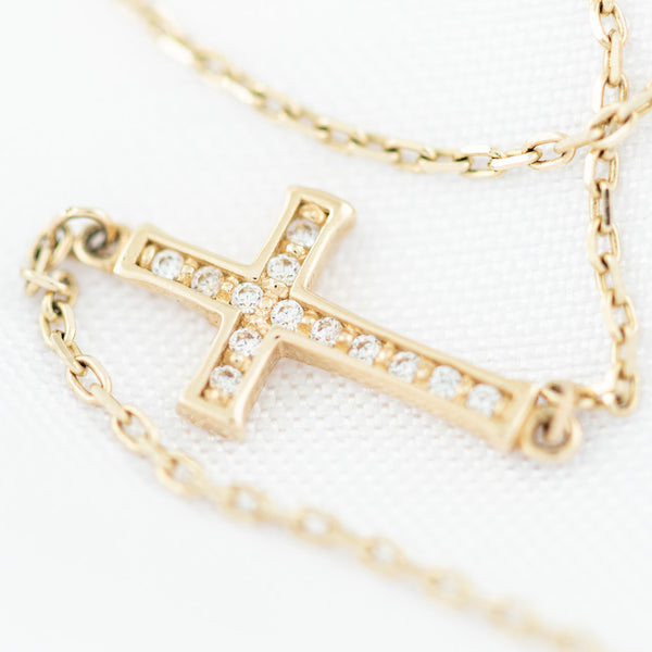 Pulsera eslabón cruzado con aplicación motivo cruz y circonias en oro amarillo 14 kilates.