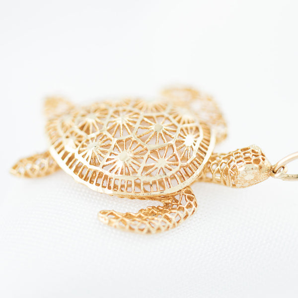 Dije calado motivo tortuga en oro amarillo 14 kilates.