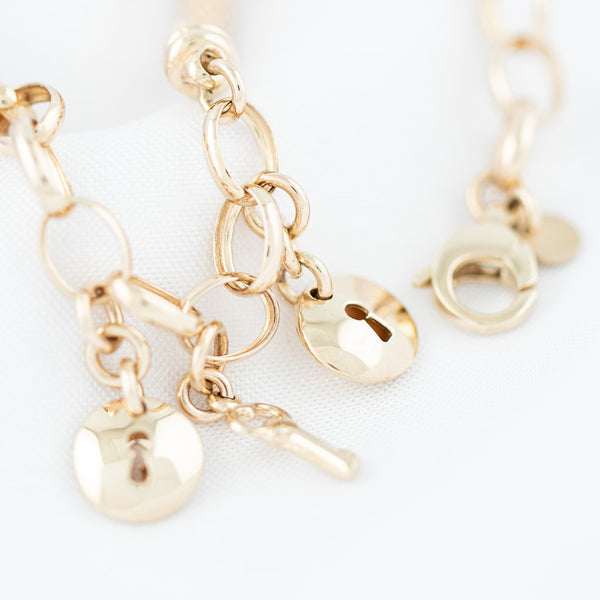 Pulsera eslabón combinado con colgantes motivo llave y cerradura en oro amarillo 14 kilates.