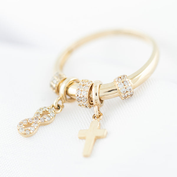 Anillo diseño especial con colgantes motivo infinito y cruz con circonias en oro amarillo 14 kilates.