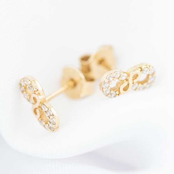 Aretes diseño especial motivo infinito con circonias en oro amarillo 14 kilates.