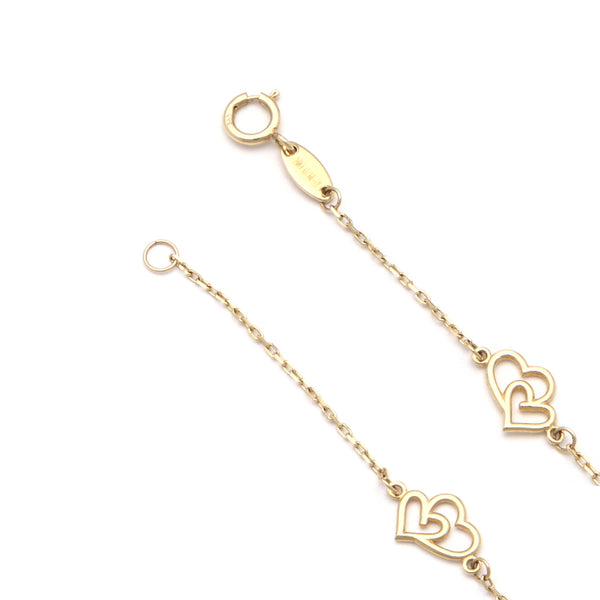Pulsera eslabón cruzado con aplicación motivo corazón doble en oro amarillo 14 kilates.
