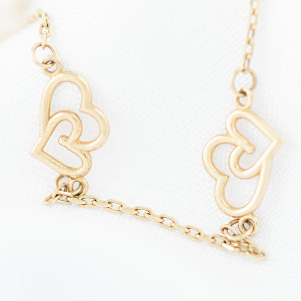 Pulsera eslabón cruzado con aplicación motivo corazón doble en oro amarillo 14 kilates.