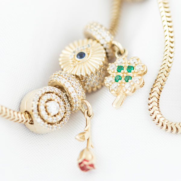 Pulsera eslabón articulado con aplicación y colgantes motivo figuras diferentes con sintéticos y esmalte en oro amarillo 14 kilates.