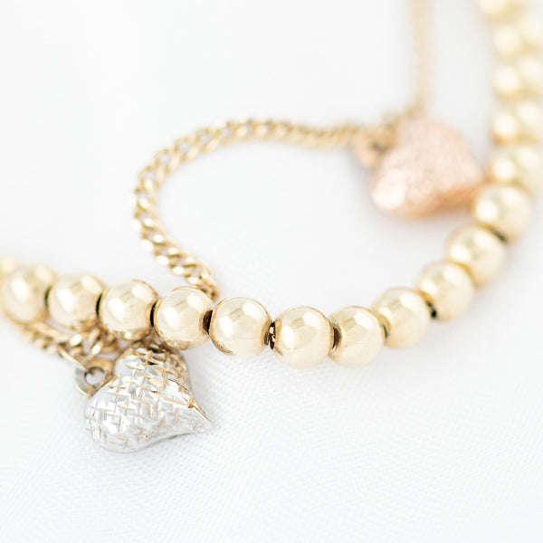 Pulsera eslabón combinado con aplicación y colgantes motivo esferas y corazón en oro amarillo 14 kilates.