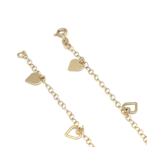 Pulsera eslabón cruzado con colgantes motivo corazón en oro amarillo 14 kilates.