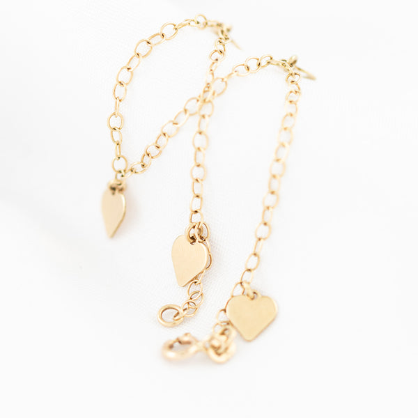 Pulsera eslabón cruzado con colgantes motivo corazón en oro amarillo 14 kilates.