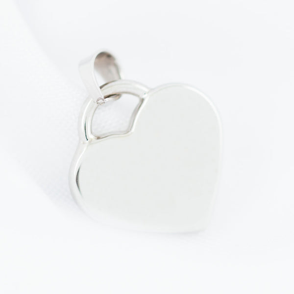 Dije liso motivo corazón en oro blanco 14 kilates.