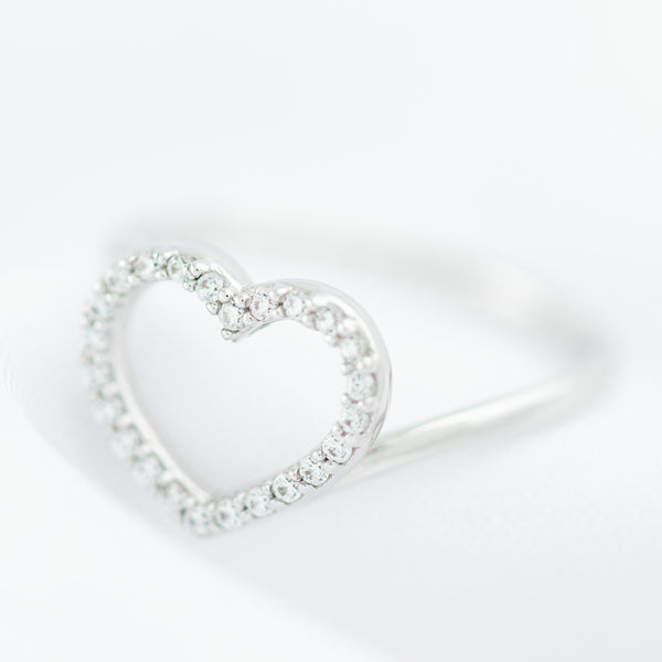 Anillo ondulado motivo corazón con sintéticos en oro blanco 14 kilates.