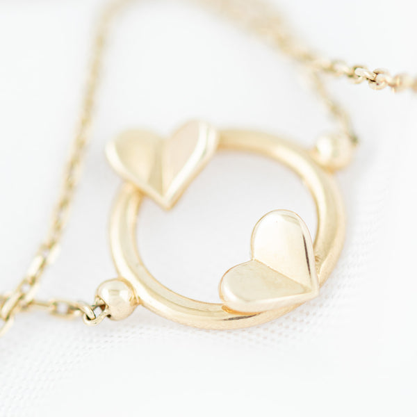 Pulsera eslabón cruzado con aplicación y colgante motivo corazones en oro amarillo 14 kilates.