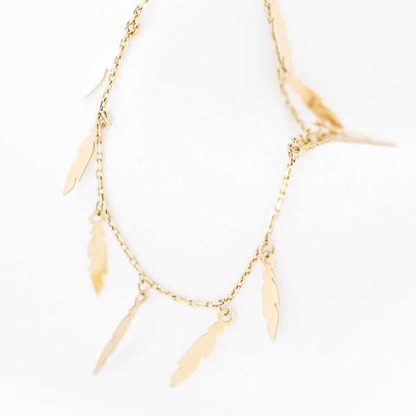 Pulsera eslabón cruzado con colgantes motivo plumas en oro amarillo 14 kilates.