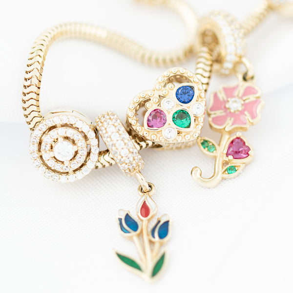 Pulsera eslabón articulado con aplicación y colgantes motivo figuras diferentes con sintéticos y esmalte en oro amarillo 14 kilates.