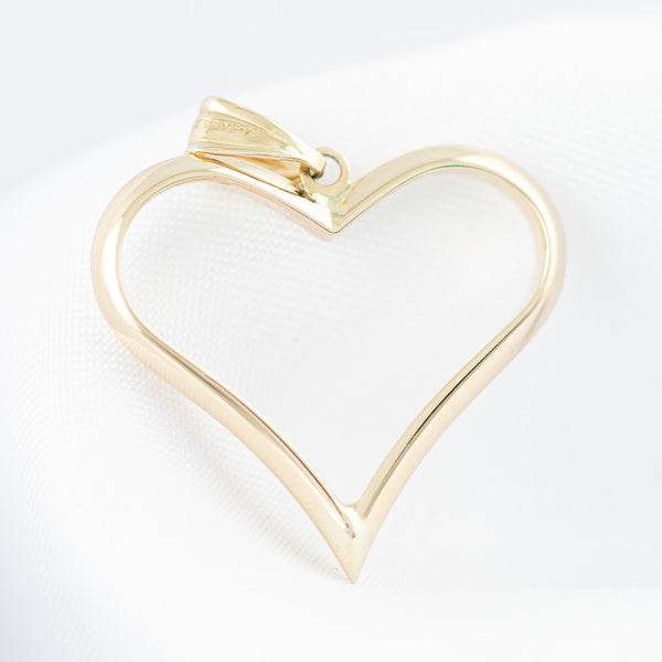Dije hueco motivo corazón en oro amarillo 14 kilates.