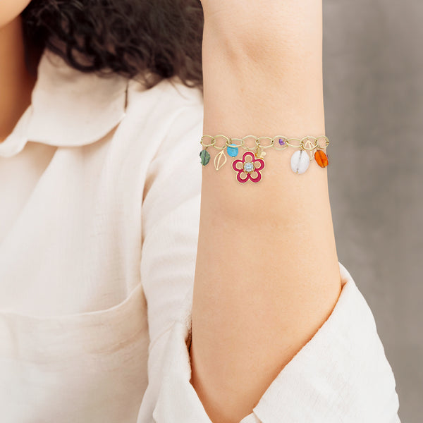 Pulsera eslabón cruzado con colgantes firma Tous motivo figuras diferentes y sintéticos en oro amarillo 18 kilates.