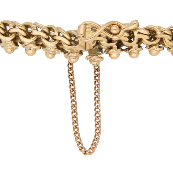 Pulsera eslabón tejido con aplicaciones y colgante con una moneda de veinte pesos oro mexicano 21.6 kilates en oro amarillo 18 kilates.