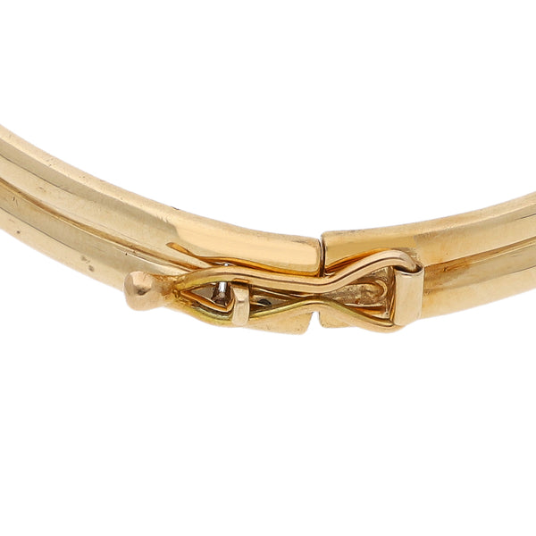 Pulsera de arillo articulada con aplicación motivo nudo y diamantes en oro amarillo 14 kilates.