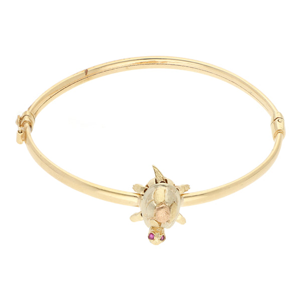 Pulsera de arillo articulada con aplicación motivo tortuga y rubíes en oro tres tonos 14 kilates.