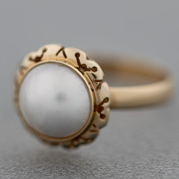 Juego de anillo y aretes calados con media perla en oro amarillo 14 kilates.