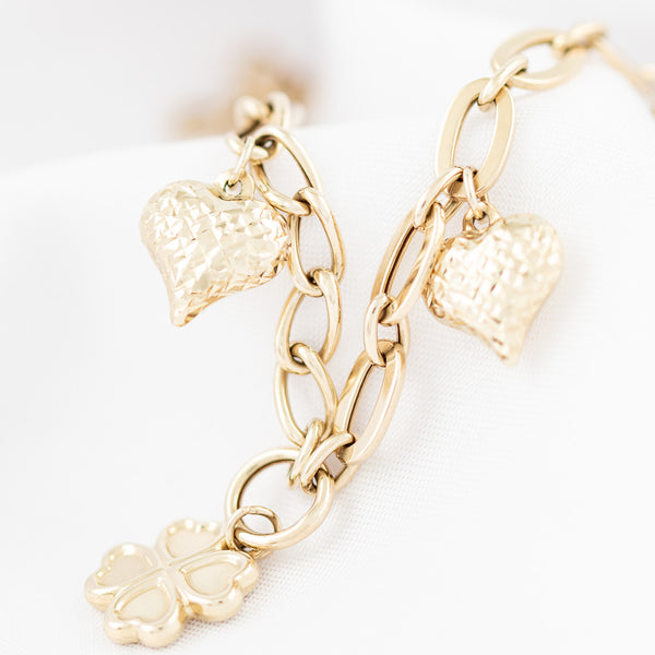 Pulsera eslabón combinado con colgantes motivo corazón y trébol en oro amarillo 14 kilates.
