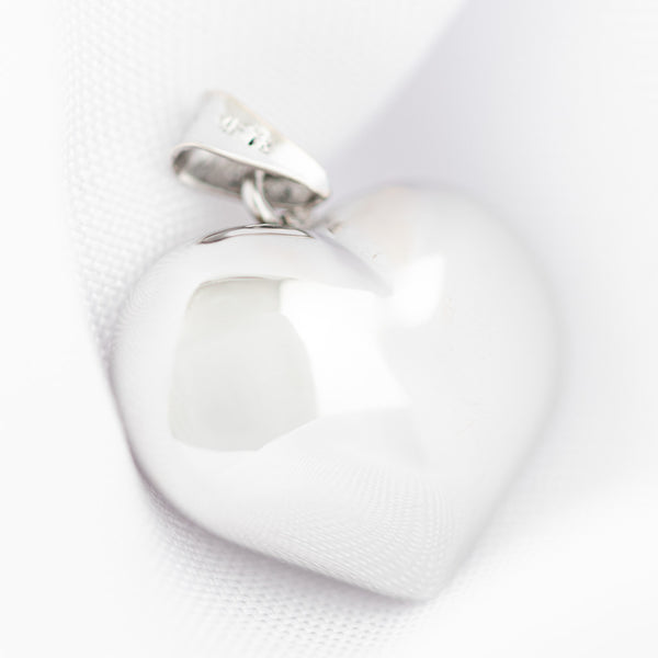 Dije hueco motivo corazón en oro blanco 14 kilates.