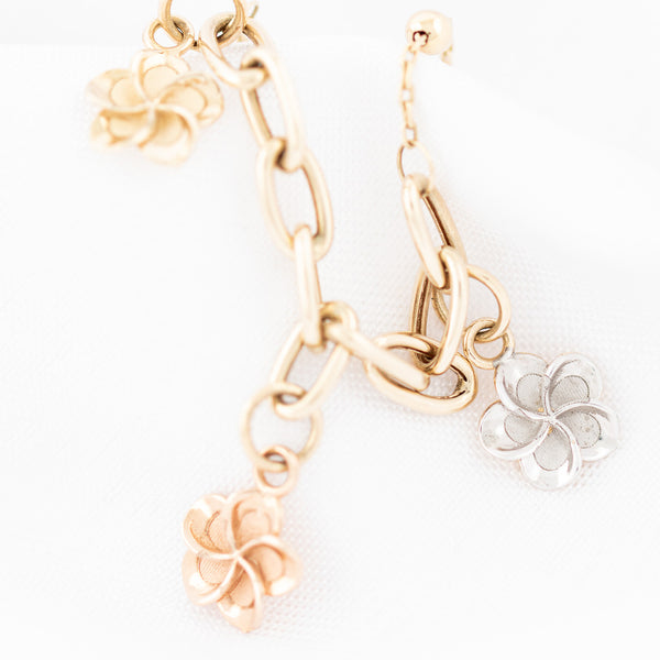 Pulsera eslabón cruzado con aplicaciones y colgantes motivo flores en oro amarillo 14 kilates.