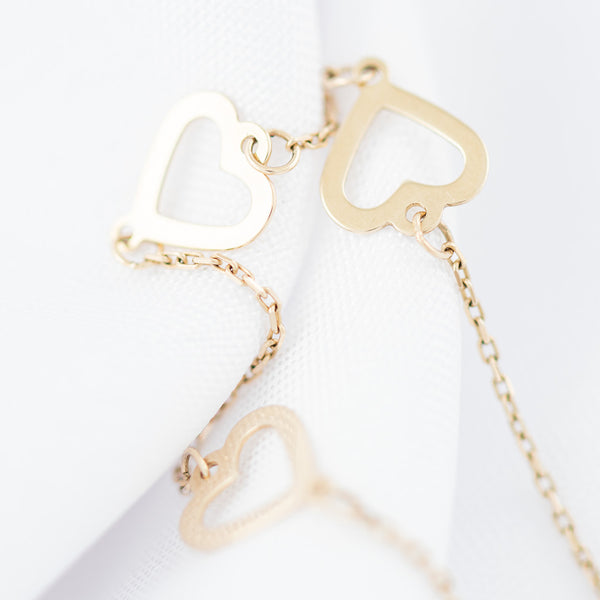 Pulsera eslabón cruzado con aplicaciones motivo corazón y sintético en oro amarillo 14 kilates.