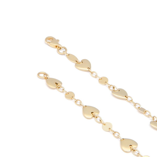 Pulsera eslabón cruzado con aplicaciones motivo corazón y círculos en oro amarillo 14 kilates.