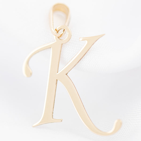 Dije liso motivo letra K en oro amarillo 14 kilates.