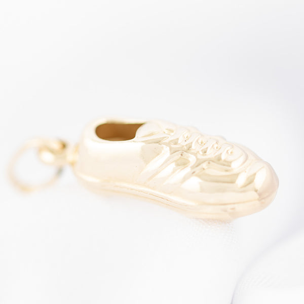 Dije hueco motivo zapato de futbol en oro amarillo 14 kilates.