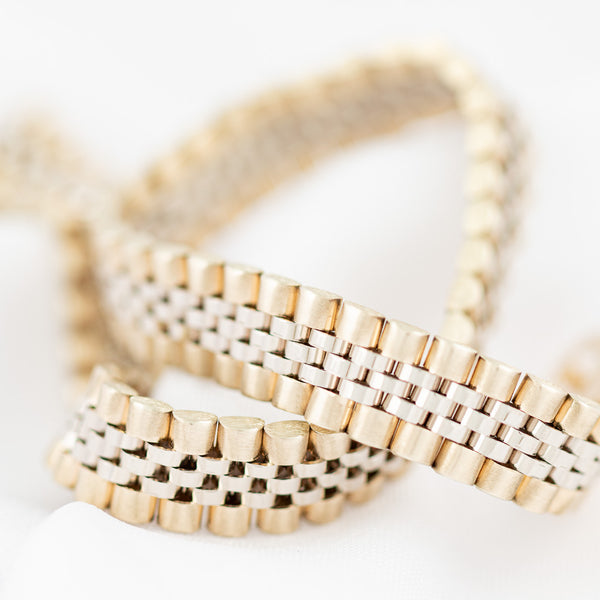 Pulsera eslabón articulado con aplicación motivo corona en oro dos tonos 14 kilates.