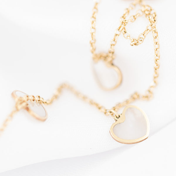 Collar eslabón cruzado con colgantes motivo corazones de madre perla en oro amarillo 14 kilates.