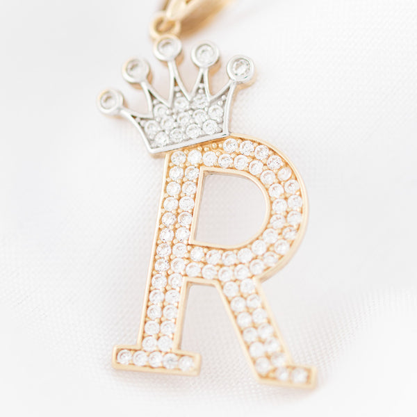 Dije diseño especial motivo letra R con corona en oro amarillo 14 kilates.