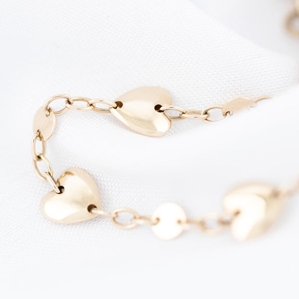 Pulsera eslabón cruzado con aplicaciones motivo corazón en oro amarillo 14 kilates.