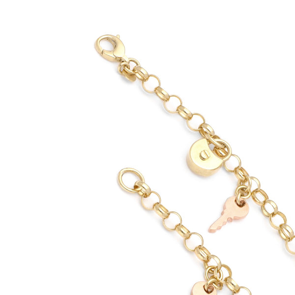 Pulsera eslabón cruzado con colgantes motivos candado y llave en oro dos tonos 14 kilates.