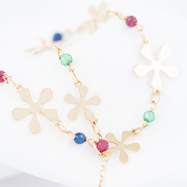 Pulsera eslabón cruzado con aplicaciones de flores y sintéticos en oro amarillo 14 kilates.
