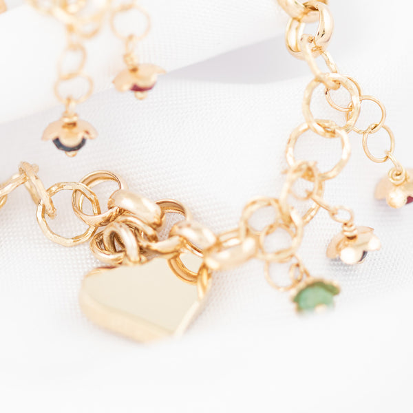 Pulsera eslabón cruzado con colgantes y circonias motivo flores y corazón en oro amarillo 14 kilates.