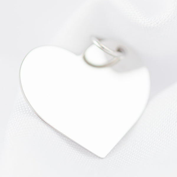 Dije liso motivo corazón en oro blanco 14 kilates.