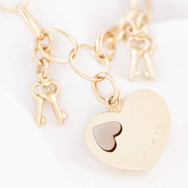 Pulsera eslabón cruzado con colgantes motivo corazón y llaves en oro amarillo 14 kilates.