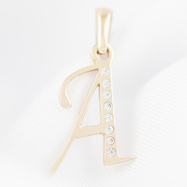 Dije liso con circonias motivo letra A oro amarillo 14 kilates.