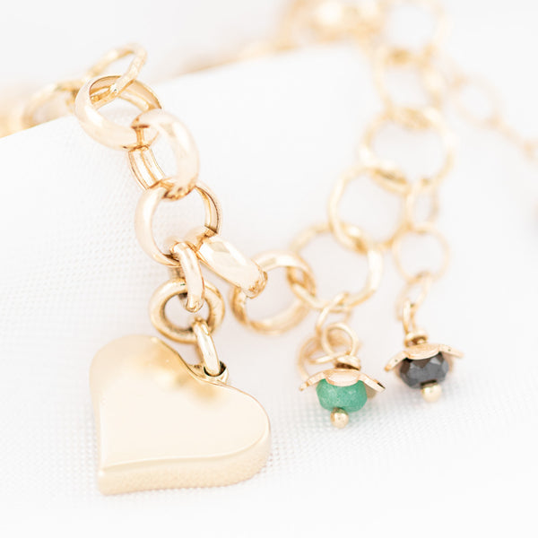 Pulsera eslabón cruzado con colgantes motivo corazón y sintéticos en oro amarillo 14 kilates.
